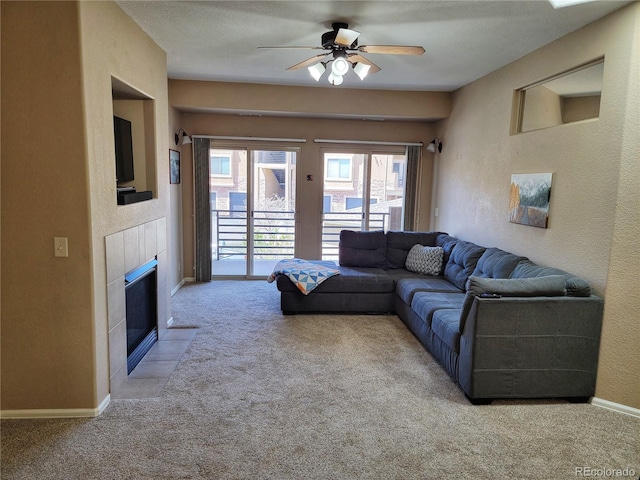 living room with a textured ceiling, a fireplace, ceiling fan, and light carpet