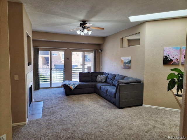 carpeted living room featuring ceiling fan, a textured ceiling, and a skylight