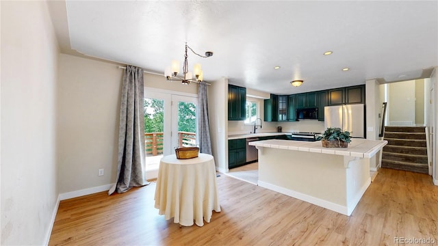 10718 Ash Ct, Thornton, CO 80233 - kitchen with stainless steel appliances, tile countertops, a chandelier, light wood-style flooring, and a kitchen island
