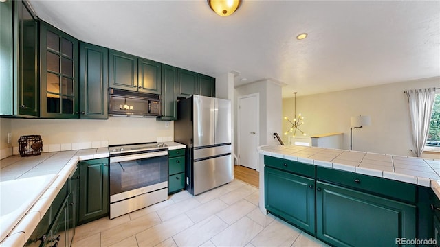 10718 Ash Ct, Thornton, CO 80233 - kitchen with appliances with stainless steel finishes, a chandelier, tile counters, green cabinets, and recessed lighting