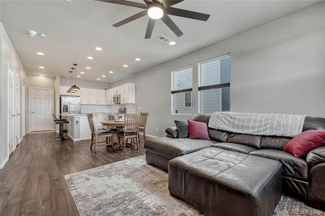 living room with dark hardwood / wood-style flooring and ceiling fan