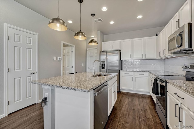 kitchen with white cabinets, decorative light fixtures, stainless steel appliances, and an island with sink