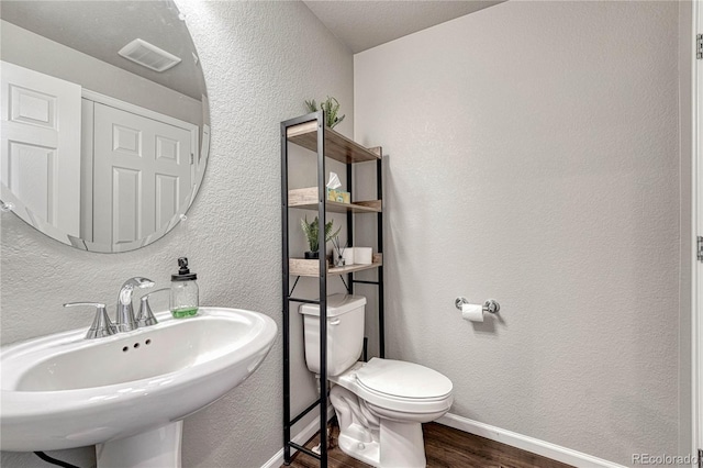 bathroom with toilet, wood-type flooring, and sink