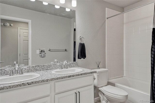 full bathroom featuring vanity, tiled shower / bath combo, and toilet