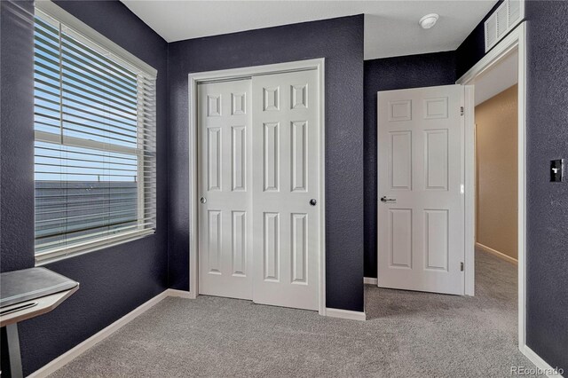 unfurnished bedroom featuring light colored carpet and a closet