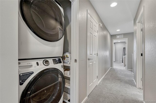 clothes washing area featuring light colored carpet and stacked washer / dryer