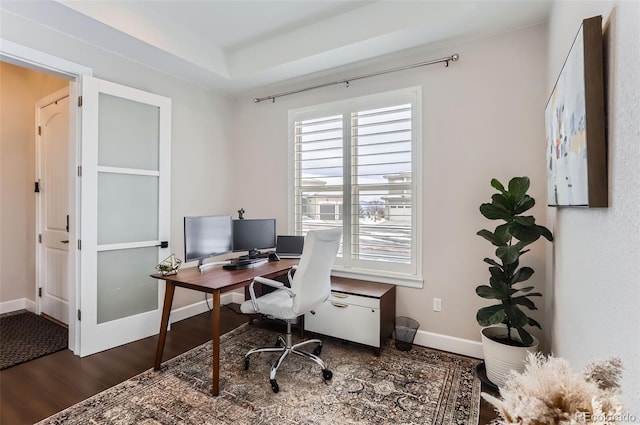 office space featuring dark wood-type flooring and a tray ceiling