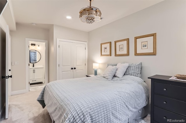 bedroom featuring a closet, ensuite bathroom, and light colored carpet