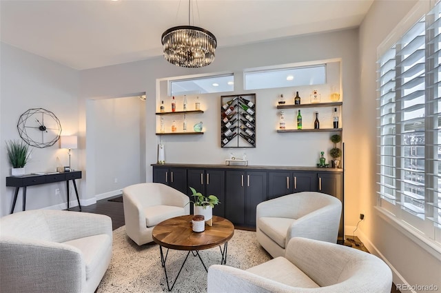 living area with a bar, light wood finished floors, baseboards, and an inviting chandelier