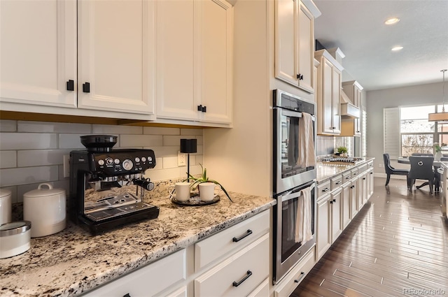 kitchen with light stone counters, stainless steel appliances, white cabinets, tasteful backsplash, and dark wood finished floors