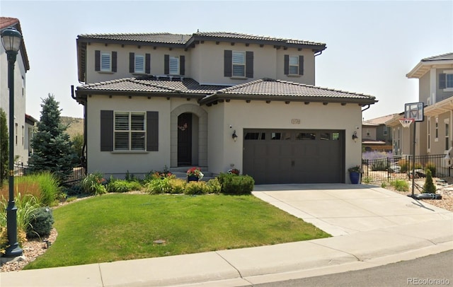 mediterranean / spanish home with a tile roof, fence, a front lawn, and concrete driveway