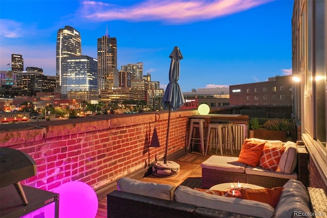 balcony at dusk featuring an outdoor fire pit and a bar