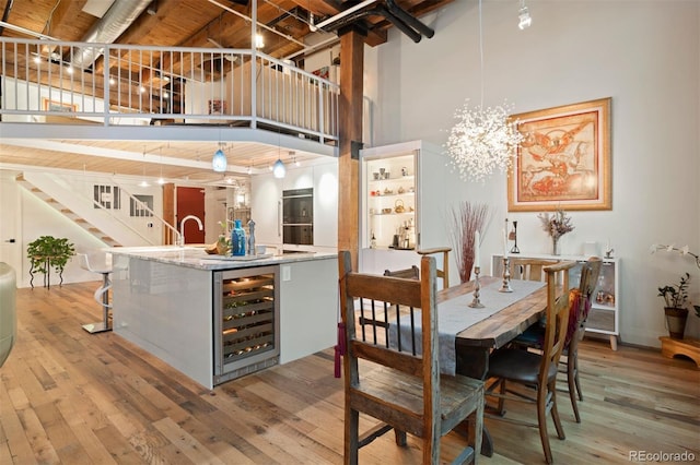 interior space featuring a high ceiling, decorative light fixtures, hardwood / wood-style flooring, and wine cooler