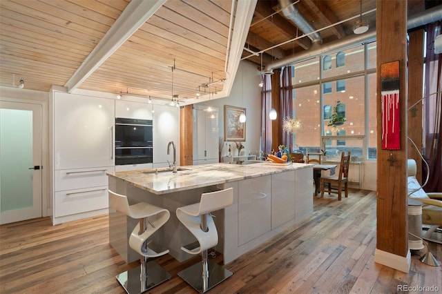 kitchen with sink, decorative light fixtures, light hardwood / wood-style floors, and wood ceiling