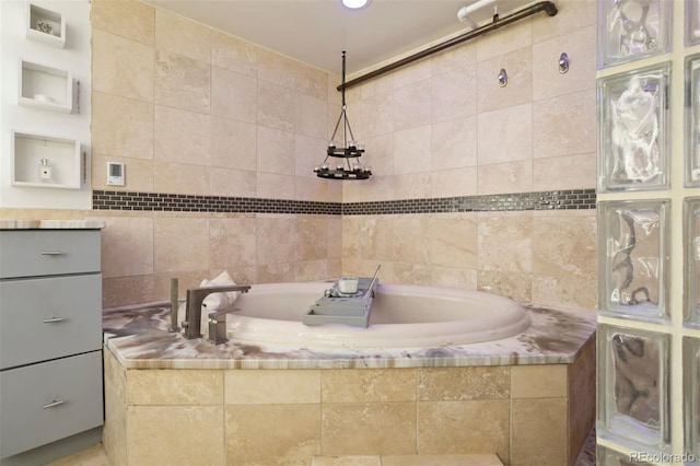 bathroom featuring tiled tub and vanity