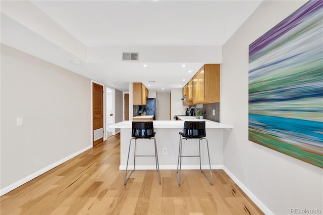 5955 E 10th Ave Unit 201, Denver, CO 80220 - kitchen with freestanding refrigerator, light countertops, a peninsula, light wood finished floors, and a kitchen breakfast bar