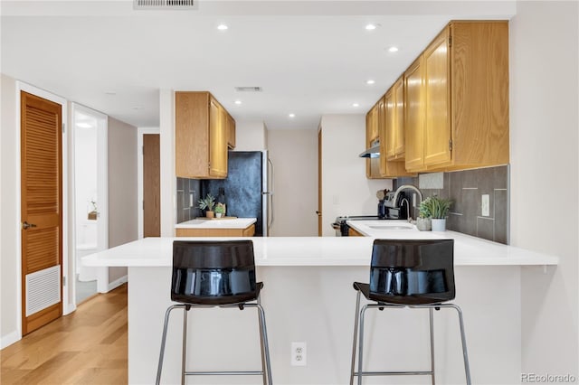 5955 E 10th Ave Unit 201, Denver, CO 80220 - kitchen with range with electric cooktop, a peninsula, freestanding refrigerator, backsplash, and under cabinet range hood