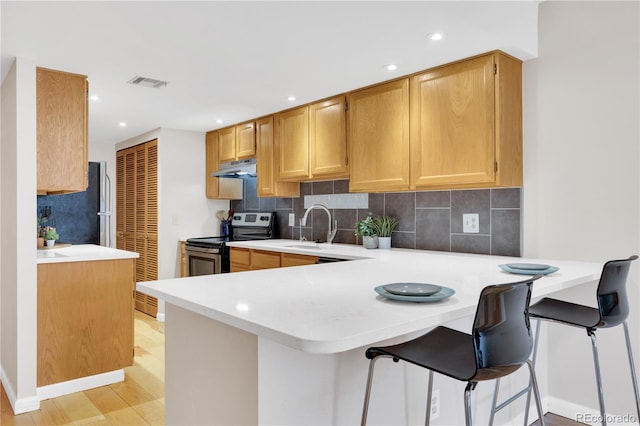 5955 E 10th Ave Unit 201, Denver, CO 80220 - kitchen featuring stainless steel range with electric cooktop, light countertops, decorative backsplash, fridge, and recessed lighting