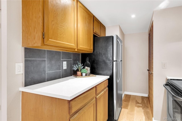 5955 E 10th Ave Unit 201, Denver, CO 80220 - kitchen featuring freestanding refrigerator, tasteful backsplash, light wood-style floors, stove, and light countertops