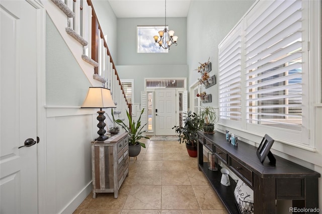 foyer featuring stairs, a high ceiling, light tile patterned floors, and a chandelier