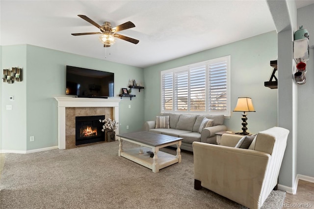 living area featuring a tiled fireplace, carpet flooring, baseboards, and ceiling fan