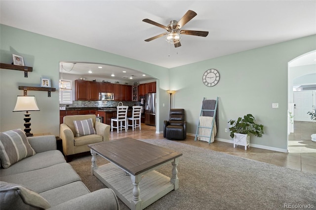 living room with a ceiling fan, recessed lighting, arched walkways, light tile patterned floors, and baseboards