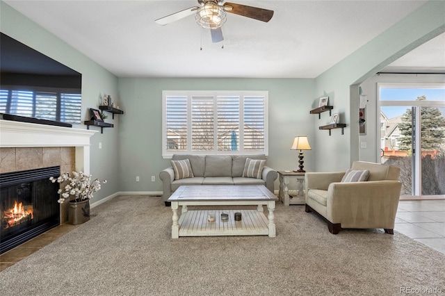 tiled living area featuring a fireplace, baseboards, and ceiling fan