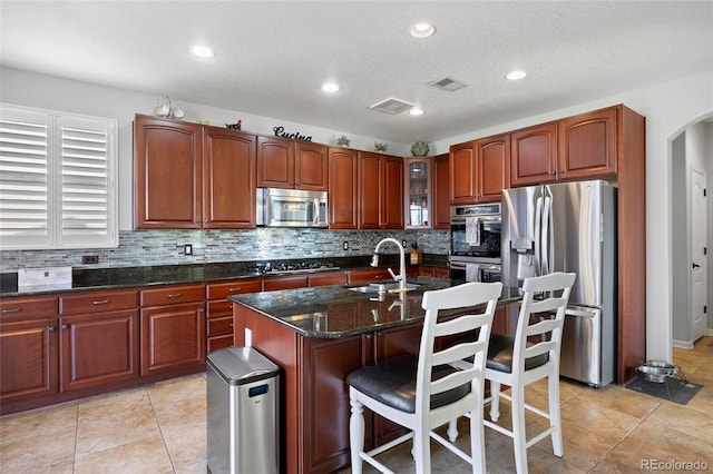 kitchen featuring a sink, backsplash, stainless steel appliances, arched walkways, and glass insert cabinets