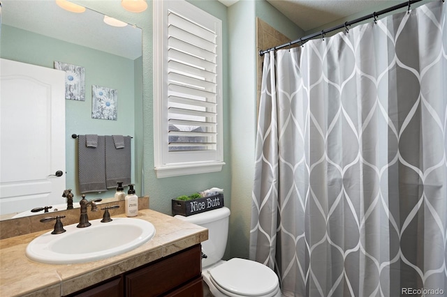 full bathroom featuring vanity, curtained shower, toilet, and a textured wall