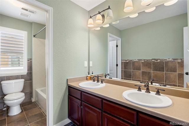 full bath with a sink, toilet, tile walls, and double vanity