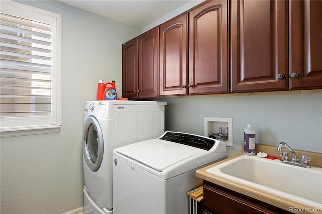 clothes washing area featuring cabinet space, washing machine and dryer, and a sink