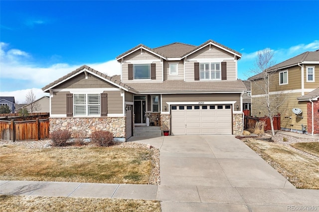 craftsman house featuring stone siding, concrete driveway, a tile roof, and fence