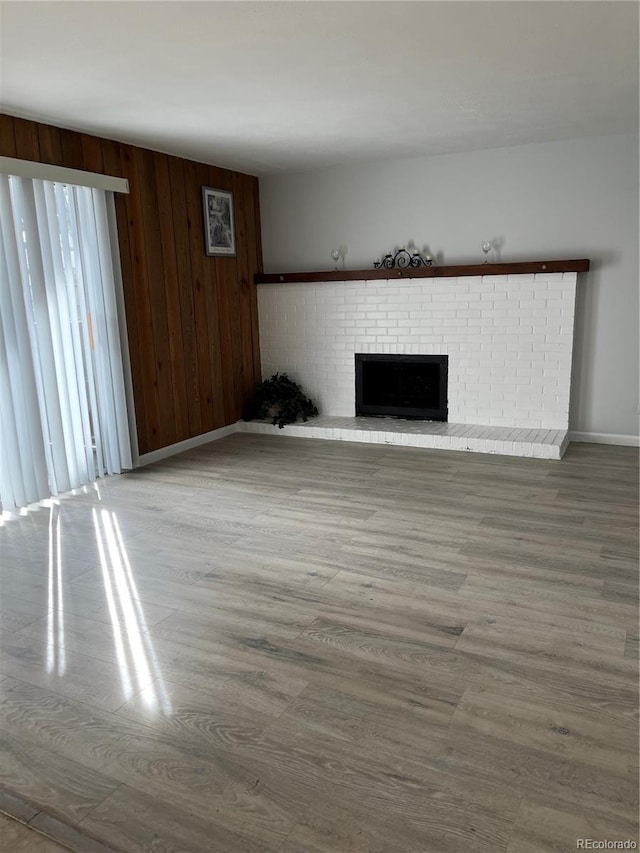9700 E Iliff Ave Unit D44, Denver, CO 80231 - unfurnished living room featuring baseboards, a brick fireplace, wood finished floors, and wooden walls