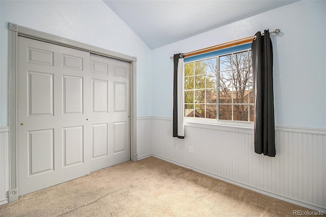 unfurnished bedroom with vaulted ceiling, carpet floors, and a closet