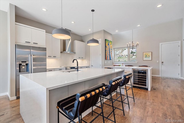 kitchen featuring a kitchen bar, a kitchen island with sink, beverage cooler, and sink