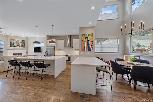 kitchen featuring an island with sink, white cabinets, pendant lighting, and hardwood / wood-style flooring