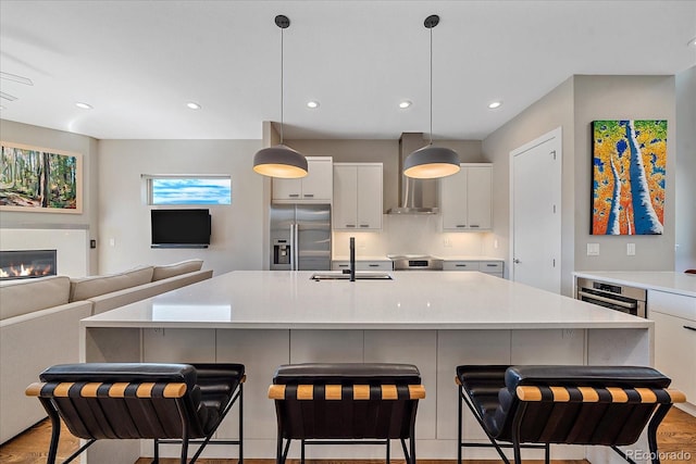 kitchen featuring sink, white cabinetry, hanging light fixtures, a center island with sink, and appliances with stainless steel finishes