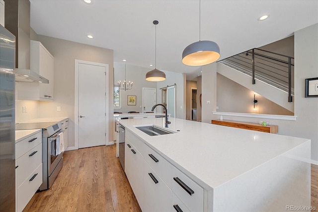 kitchen with pendant lighting, sink, a large island, white cabinetry, and light hardwood / wood-style floors