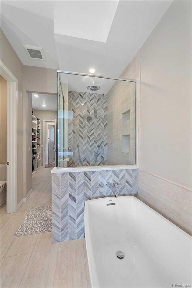 bathroom with tile walls, toilet, tile patterned floors, and separate shower and tub