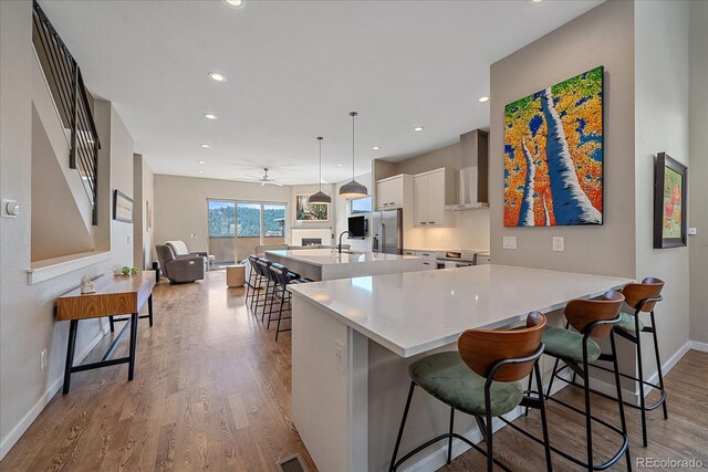756 Dreamcatcher Ln, Evergreen, CO 80439 - kitchen featuring stainless steel appliances, white cabinets, wall chimney exhaust hood, baseboards, and ceiling fan
