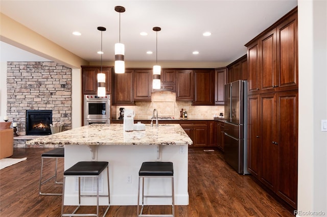 kitchen with pendant lighting, sink, appliances with stainless steel finishes, a kitchen breakfast bar, and an island with sink