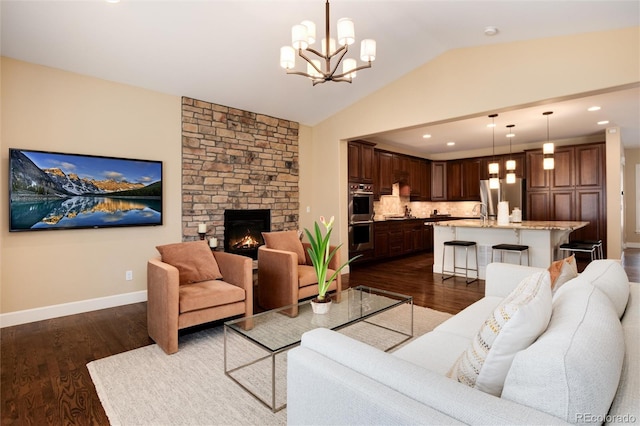 living room with vaulted ceiling, dark wood-type flooring, a chandelier, and a fireplace