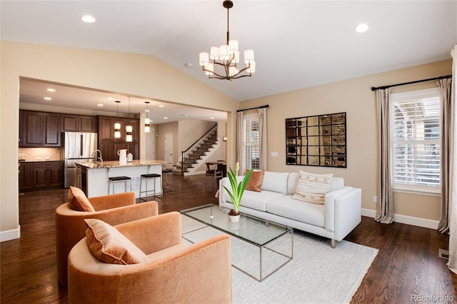 living room featuring lofted ceiling, dark wood-type flooring, and a notable chandelier