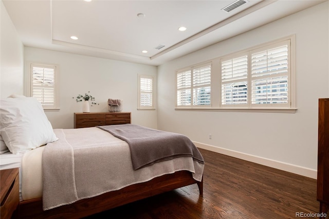 bedroom featuring a raised ceiling and dark hardwood / wood-style flooring