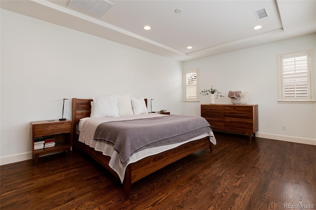 bedroom with dark hardwood / wood-style flooring and a raised ceiling