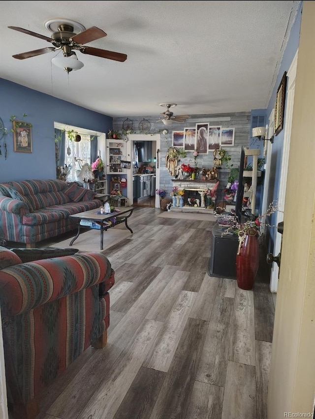 living area featuring wood finished floors, a textured ceiling, and a ceiling fan