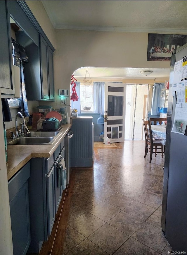 kitchen featuring stainless steel dishwasher, a sink, and ornamental molding