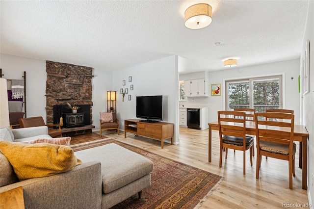 living room featuring a textured ceiling, light wood-type flooring, and a wood stove