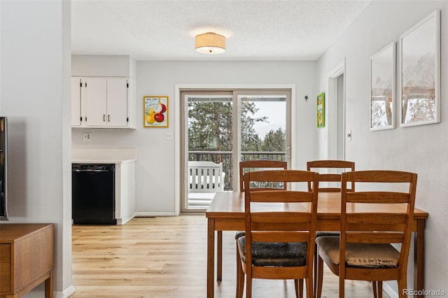 dining area with baseboards, a textured ceiling, and light wood finished floors