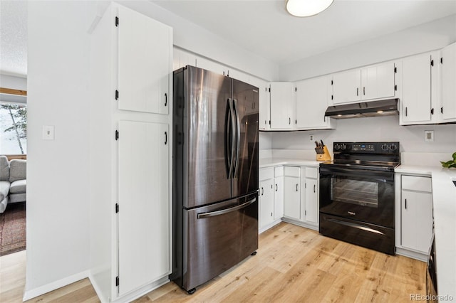 kitchen with under cabinet range hood, electric range, light wood-type flooring, and freestanding refrigerator